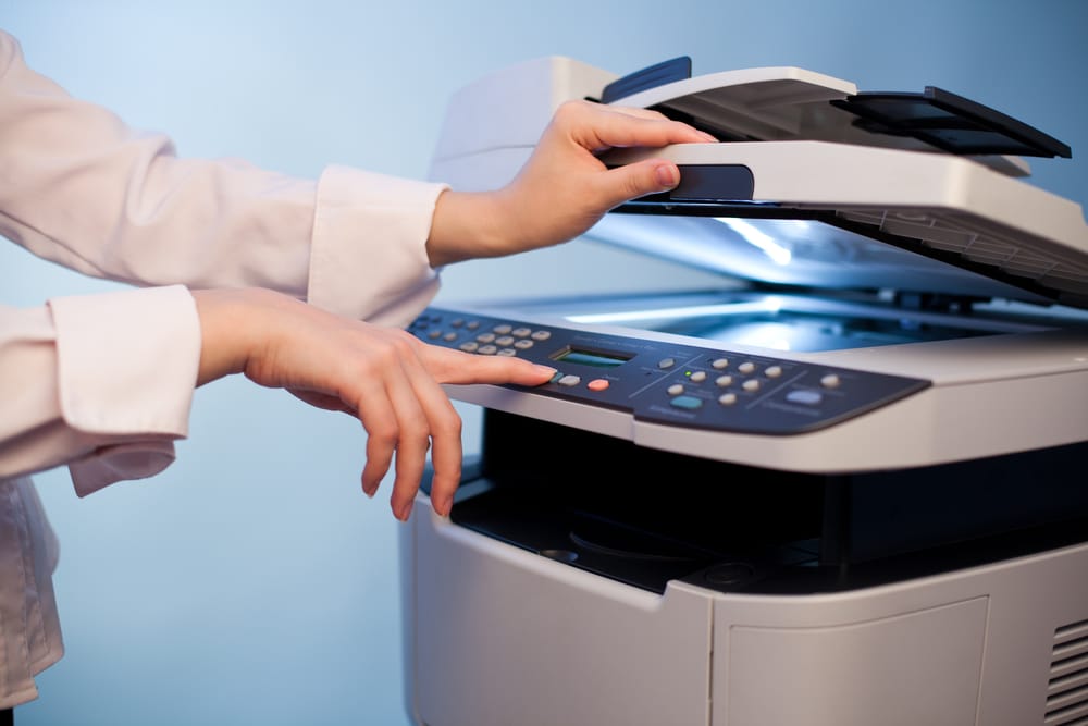Close-up of female hand using copier machine in office